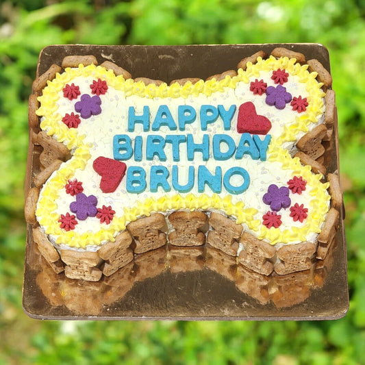 A themed birthday cake designed to look like a bone, with 'Happy Birthday' and your pet's written on top