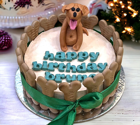 A decorated cake with a dog figurine on top, and 'happy birthday' text in blue icing.